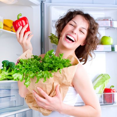 Dieting concept .Diet. Beautiful Young Woman near the Refrigerat Dieting concept .Diet. Beautiful Young Woman near the Refrigerator with healthy food. Fruits and Vegetables